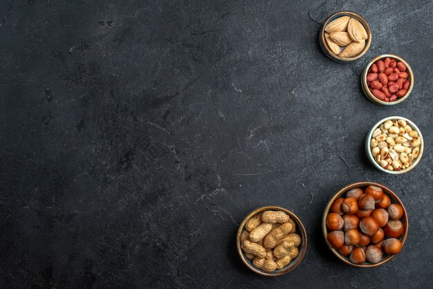 Draufsicht verschiedene Nüsse Haselnüsse und Erdnüsse auf der grauen Hintergrundnuss-Snack-Walnuss-Nahrungspflanze