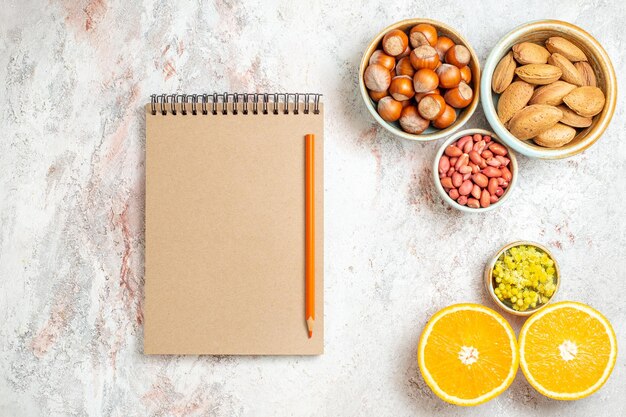 Draufsicht verschiedene Nüsse mit in Scheiben geschnittener Orange auf weißem Hintergrund Obst Zitrus Nuss Snack