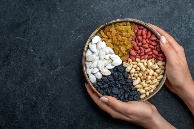 Draufsicht verschiedene Nüsse mit Rosinen und getrockneten Früchten auf dem grauen Schreibtischnuss-Snack Haselnuss-Walnuss-Erdnuss