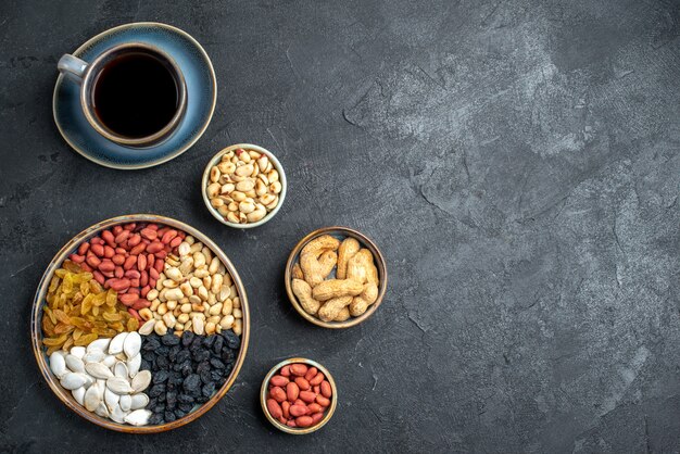 Draufsicht verschiedene Nüsse mit Rosinen und Tasse Kaffee auf der dunkelgrauen Hintergrundnuss-Snack-Walnuss-Erdnuss