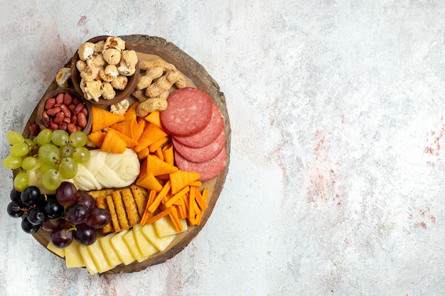 Draufsicht verschiedene Snacks Nüsse Cips Trauben Käse und Würstchen auf dem weißen Hintergrund Nuss Snack Mahlzeit Lebensmittel Früchte