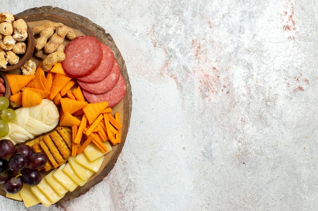 Draufsicht verschiedene Snacks Nüsse Cips Trauben Käse und Würstchen auf weißen Schreibtisch Nuss Snack Mahlzeit Lebensmittel Früchte