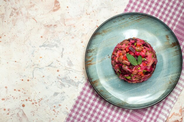 Draufsicht-Vinaigrette-Salat auf ovaler Platte lila weiß karierte Tischdecke auf hellgrauem Tischkopierplatz