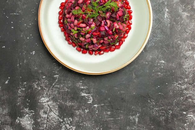 Draufsicht-Vinaigrette-Salat mit Granatäpfeln und Bohnen auf dunkler Oberfläche