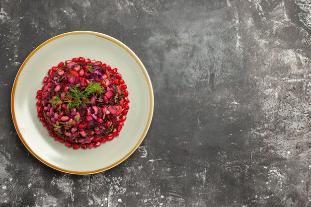 Draufsicht-Vinaigrette-Salat mit Granatäpfeln und Bohnen auf grauer Oberfläche