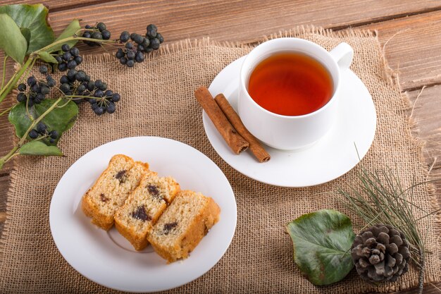 Draufsicht von Biskuitscheiben auf einem Teller mit einer Tasse schwarzen Tees auf rustikalem Hintergrund