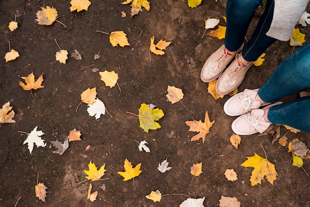 Draufsicht von Blättern auf Boden und Füßen von zwei Mädchen