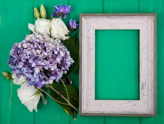 Draufsicht von Blumen und Rahmen auf grünem Hintergrund mit Kopienraum