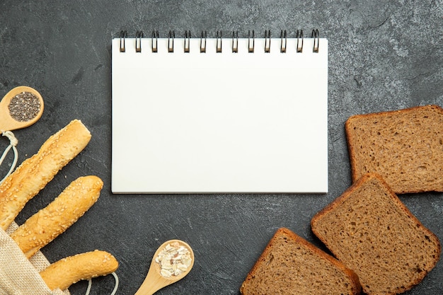 Draufsicht von Brötchenbrot mit dunklen Brotlaibs auf dunkelgrauer Oberfläche