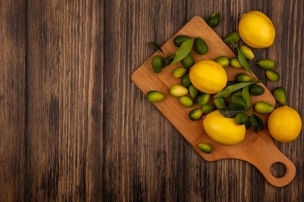 Draufsicht von bunten Früchten wie Zitronen und Kinkans auf einem hölzernen Küchenbrett auf einer hölzernen Oberfläche mit Kopierraum