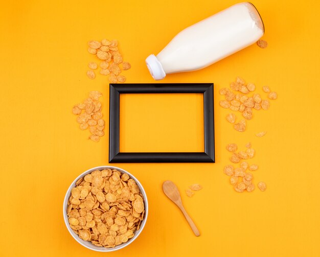 Draufsicht von Cornflakes und Milch mit Kopienraum im schwarzen Rahmen und im gelben Hintergrund horizontal