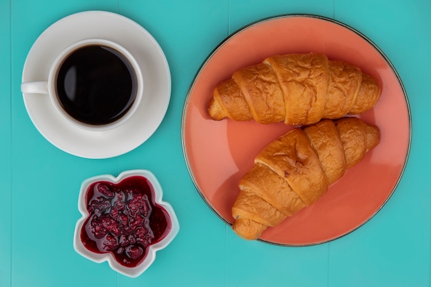 Kostenloses Foto draufsicht von croissants und himbeermarmelade mit tasse tee auf blauem hintergrund