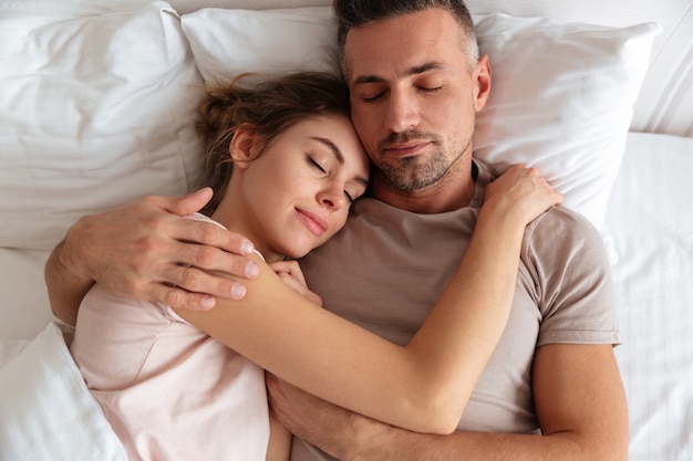 Draufsicht von den hübschen liebevollen Paaren, die zusammen zu Hause im Bett schlafen