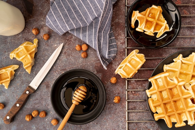 Kostenloses Foto draufsicht von den waffeln bedeckt im honig mit haselnüssen und honigschöpflöffel