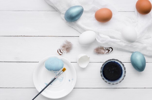 Draufsicht von Eiern für Ostern mit Farbe und Federn