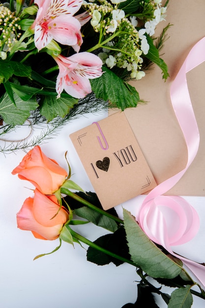 Draufsicht von einem Blumenstrauß der rosa Farbe Alstroemeria Blumen mit blühendem Viburnum und einer Postkarte mit Korallenfarbe Rosen auf weißem Hintergrund