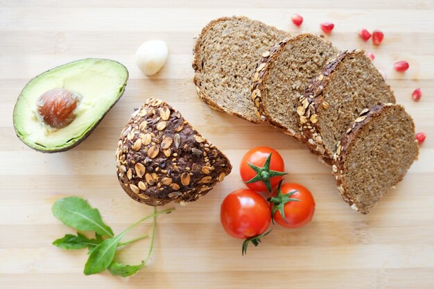 Draufsicht von einigen Avocado-Tomaten und Brot auf einem Schneidebrett