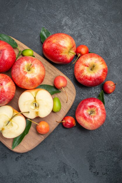 Draufsicht von fernen Fruchtäpfeln mit Blattfrüchten und Beeren auf dem Holzbrett