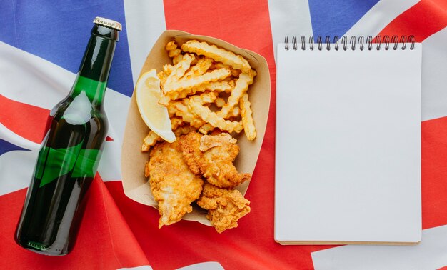 Draufsicht von Fish and Chips auf Teller mit Notizbuch und Bierflasche