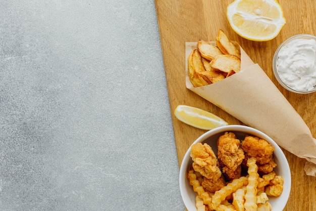 Draufsicht von Fish and Chips in Schüssel und Papierumhüllung mit Kopienraum