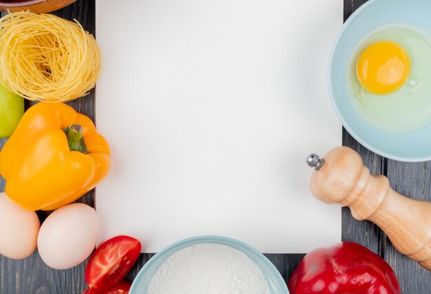 Draufsicht von frischem Eigelb und Weiß auf einer Schüssel mit Salzstreuer mit einem orangefarbenen Paprika auf einem hölzernen Hintergrund mit Kopienraum