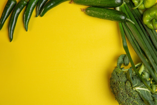 Draufsicht von frischem Gemüse grünem Chili-Pfeffer und Gurken mit Kopienraum auf Gelb