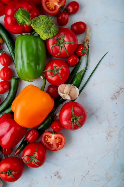 Draufsicht von frischem reifem Gemüse Tomaten grüner Chili Pfeffer Paprika Knoblauch Brokkoli und Zwiebel auf Marmorhintergrund