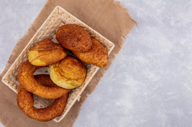 Draufsicht von frischen Brötchen auf einem Eimer auf einem Sackstoff auf einem weißen Hintergrund mit Kopienraum