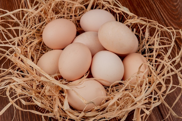 Kostenloses Foto draufsicht von frischen mehreren hühnereiern auf nest auf hölzernem hintergrund