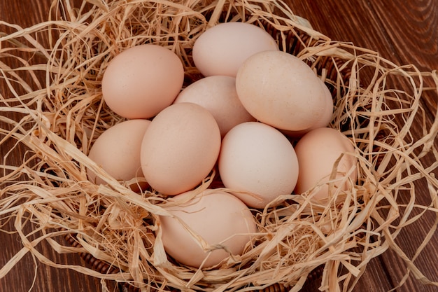 Draufsicht von frischen mehreren Hühnereiern auf Nest auf hölzernem Hintergrund
