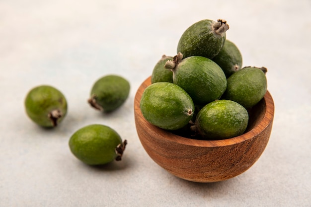 Draufsicht von frischen reifen Feijoas auf einer Holzschale mit Feijoas lokalisiert auf einer grauen Wand