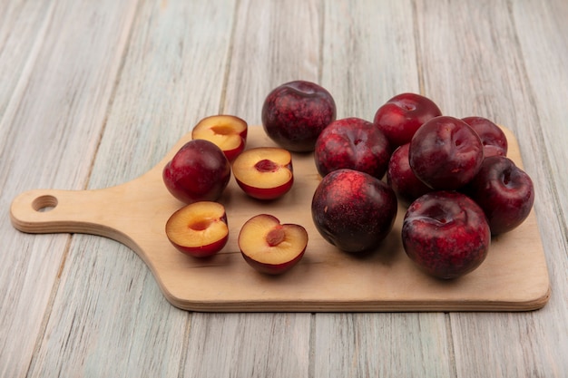 Kostenloses Foto draufsicht von frischen und saftigen pluots lokalisiert auf einem hölzernen küchenbrett auf einem grauen hölzernen hintergrund