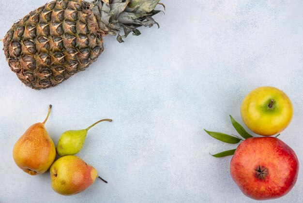 Draufsicht von Früchten als Ananas, Granatapfel, Apfel, Birnen und Pfirsich auf weißer Oberfläche