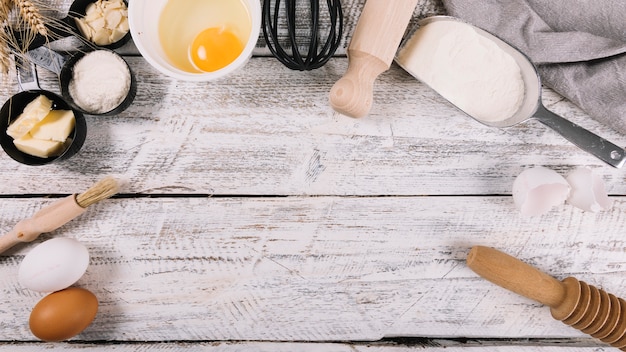 Draufsicht von gebackenen Bestandteilen mit Küchenausrüstungen auf weißem Holztisch