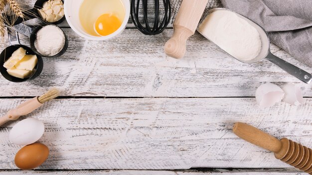 Draufsicht von gebackenen Bestandteilen mit Küchenausrüstungen auf weißem Holztisch