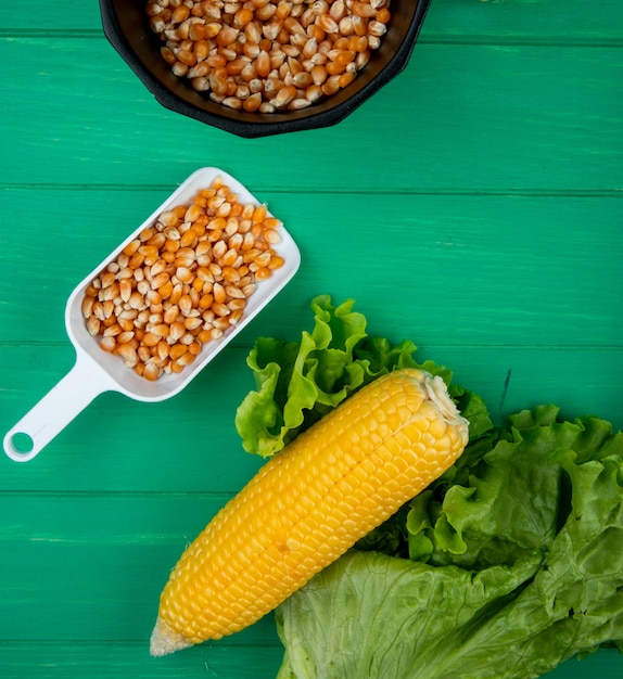 Draufsicht von gekochtem Mais mit Salat und Löffel voll von Maissamen auf Grün