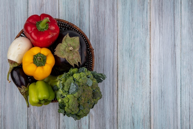 Draufsicht von Gemüse als Brokkoli-Pfeffer und Aubergine im Korb auf hölzernem Hintergrund mit Kopienraum