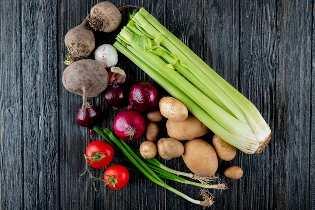 Draufsicht von Gemüse als Sellerie-Rote-Bete-Knoblauch-Zwiebel-Tomate und Frühlingszwiebel auf hölzernem Hintergrund mit Kopienraum