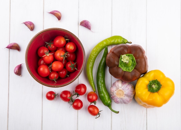 Draufsicht von Gemüse als Tomaten in Schüssel Paprika Knoblauchknolle und Nelken auf Holzoberfläche