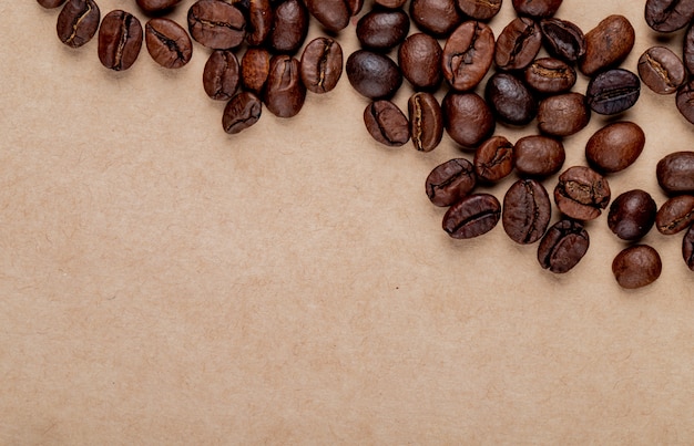 Draufsicht von gerösteten Kaffeebohnen verstreut auf braunem Papierbeschaffenheitshintergrund mit Kopienraum