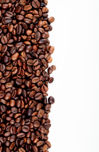 Draufsicht von gerösteten Kaffeebohnen verstreut auf weißem Hintergrund mit Kopienraum