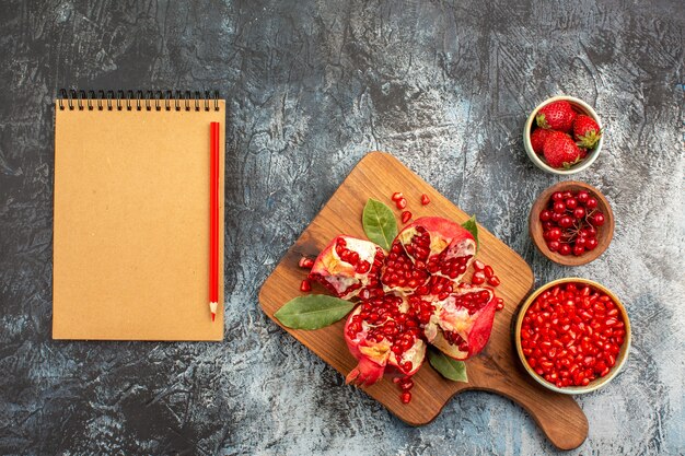 Draufsicht von geschnittenen Granatäpfeln mit roten Früchten auf dunklem Hintergrund