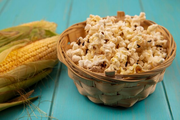 Draufsicht von gesunden Körnern mit Haaren mit Popcorn auf einem Eimer auf einem blauen Holztisch