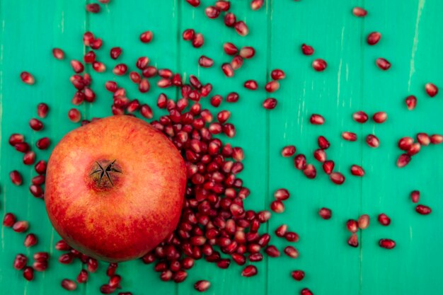 Draufsicht von Granatapfel und Granatapfelbeeren auf grüner Oberfläche