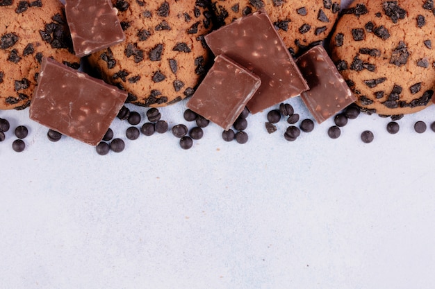 Draufsicht von Haferkeksen mit Schokoladenstückchen und dunklen Schokoladenstücken auf weißem Hintergrund mit Kopienraum