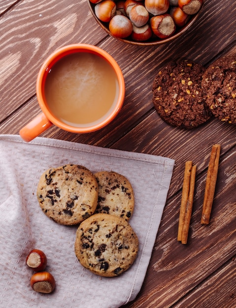 Draufsicht von Haferkeksen mit Schokoladenstückchen und einer Tasse Kakaogetränk auf einem Holz