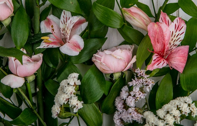 Draufsicht von hellrosa Blumen mit Blättern auf einer grauen Oberfläche