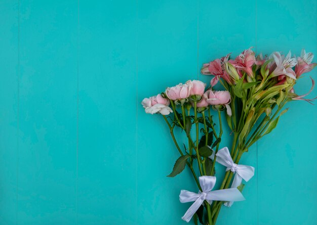 Draufsicht von hellrosa Rosen mit Lilien auf einer hellblauen Oberfläche