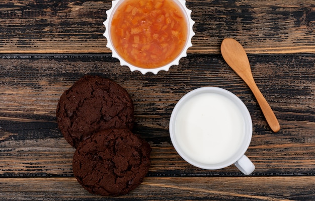 Draufsicht von Keksen mit Milch und Marmelade auf dunkler Holzoberfläche horizontal