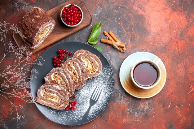 Draufsicht von Keksröllchen mit Tasse Tee auf dunkler Oberfläche